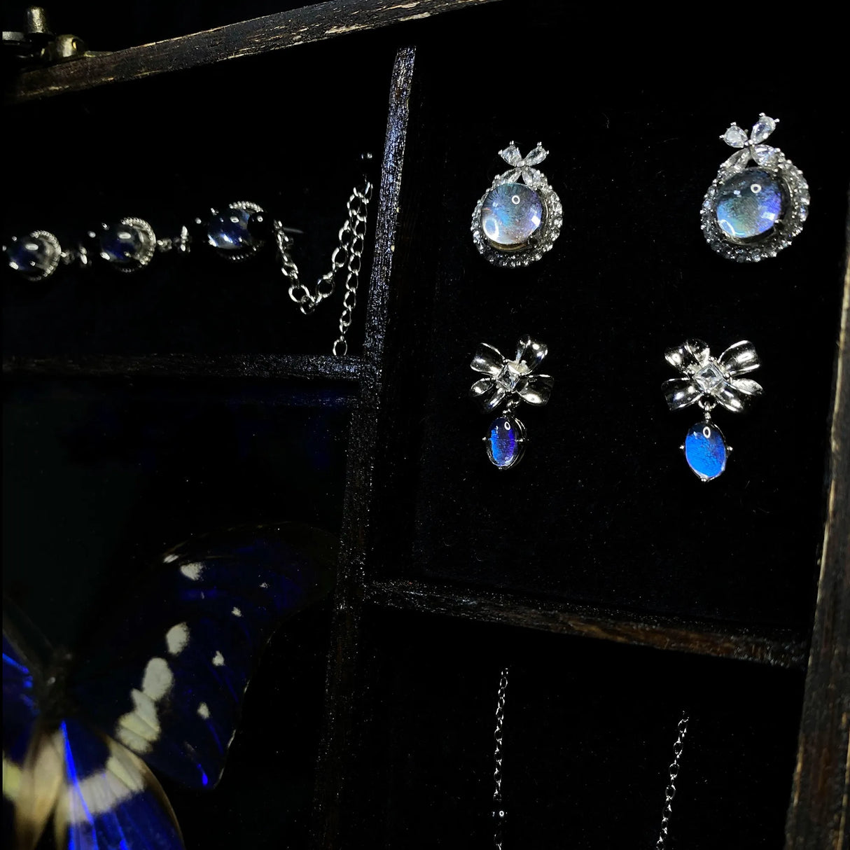 Close-up of handmade jewelry crafted from genuine Morpho helena butterfly wings showing natural iridescent blue coloration.
