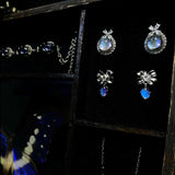 Close-up of handmade jewelry crafted from genuine Morpho helena butterfly wings showing natural iridescent blue coloration.